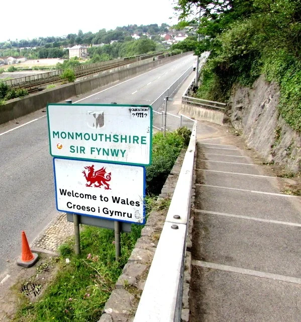 Eine Wissenschaftlerin und ein Wissenschaftler arbeiten hinter einer Glasfassade und mischen Chemikalien mit Großgeräten.