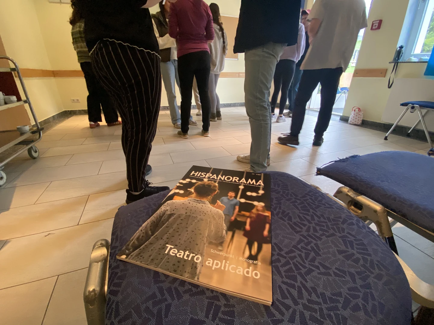 Eine Wissenschaftlerin und ein Wissenschaftler arbeiten hinter einer Glasfassade und mischen Chemikalien mit Großgeräten.